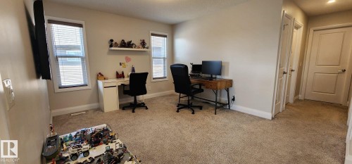 Carpeted room with two windows featuring blinds, a built-in wall shelf, and light-colored walls - 3779 Cherry Loop Sw, Edmonton, AB 
