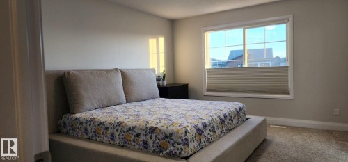 Carpeted room featuring a large window with horizontal blinds, light-toned walls, and a built-in recessed light fixture - 3779 Cherry Loop Sw, Edmonton, AB 