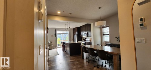 Open-concept living area with wood-finish flooring, recessed lighting, and a drum pendant light fixture - 3779 Cherry Loop Sw, Edmonton, AB 