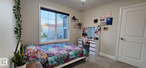 Window with white frame, light gray walls, built-in vanity with drawers, white interior door with paneling, and gray carpeted flooring - 3779 Cherry Loop Sw, Edmonton, AB 