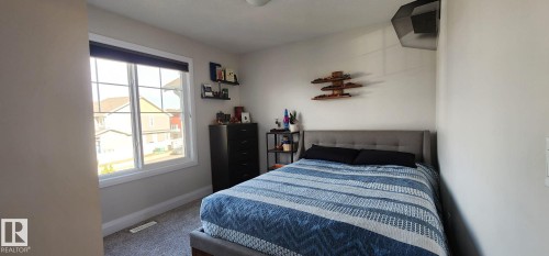 Carpeted room featuring a double-paned window, neutral wall paint, and a built-in light fixture - 3779 Cherry Loop Sw, Edmonton, AB 