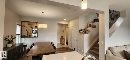 Open-concept living area featuring wood-finish flooring, a contemporary drum pendant light, recessed lighting, and a carpeted staircase with built-in wall shelving - 3779 Cherry Loop Sw, Edmonton, AB 