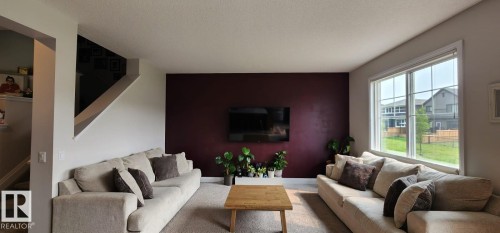Expansive living area with a large picture window, a deep accent wall, and recessed lighting - 3779 Cherry Loop Sw, Edmonton, AB 
