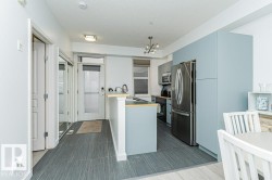 Modern kitchen featuring light blue cabinetry, stainless steel appliances, and a breakfast bar - 