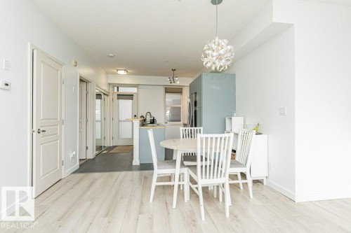 Light wood-finish flooring throughout, bright white walls, and a modern pendant light fixture - #202 9503 101 Av Nw, Edmonton, AB 