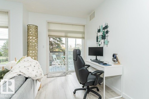 Light wood-finish flooring, white walls, and a sliding glass door leading to a balcony - #202 9503 101 Av Nw, Edmonton, AB 