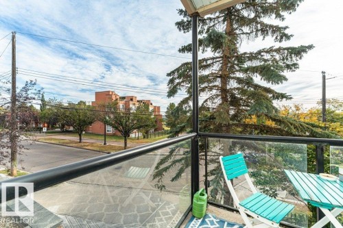 Balcony featuring glass panel railing, black metal framing, and a patterned floor - #202 9503 101 Av Nw, Edmonton, AB 