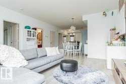 Open-concept living space featuring wood-finish flooring, recessed lighting, and a modern dining area chandelier - 