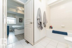 White tiled flooring leading to a bedroom with wood-finish flooring, a window with blinds, and a built-in ceiling light fixture - 