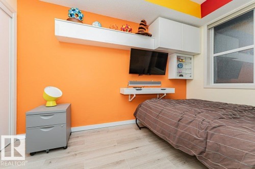 Wall-mounted storage cabinetry and shelving, a built-in wall-mounted desk, and a window with white trim - #202 9503 101 Av Nw, Edmonton, AB 