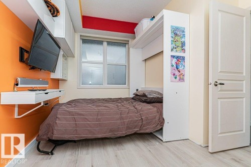Built-in bed frame with overhead storage, wood-finish flooring, and a window with white trim - #202 9503 101 Av Nw, Edmonton, AB 