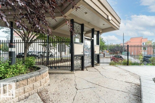 Covered entryway with decorative wrought iron gate and a stone-faced planter - #202 9503 101 Av Nw, Edmonton, AB 