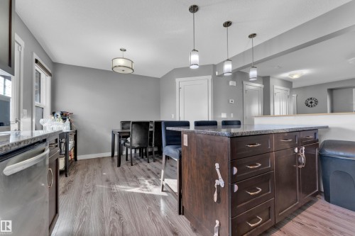 Kitchen island with stone countertop, wood-finish flooring, stainless steel appliances, pendant lighting, and recessed lighting - #22 4205 30 St Nw, Edmonton, AB 