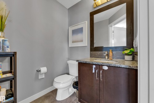Powder room featuring a dark wood-finish vanity, light-toned countertop, rectangular sink, and mosaic tile backsplash - #22 4205 30 St Nw, Edmonton, AB 