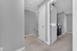 Carpeted hallway with white trim, solid core doors, and a staircase with a handrail - 