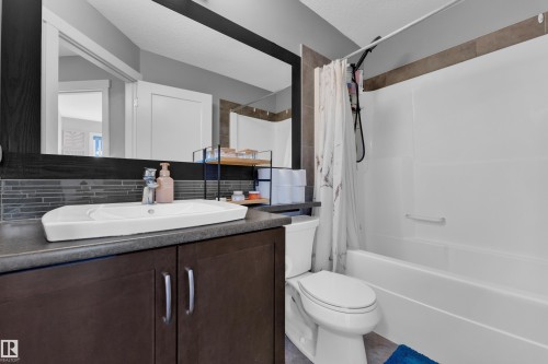 Integrated bathtub and shower combination with full-height tile surround, dark wood-finish vanity with countertop, and rectangular vessel sink - #22 4205 30 St Nw, Edmonton, AB 