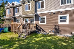 Expansive rear deck with wooden railing and steps, offering direct access to a green lawn - 