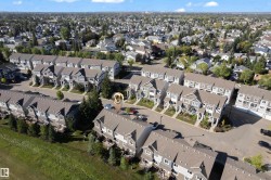 Aerial perspective of a multi-unit residential development with pitched roofs and established landscaping - 