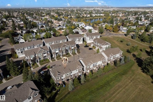 Aerial perspective showcasing a residential development with multiple townhome units, surrounded by landscaped green spaces and mature trees - #22 4205 30 St Nw, Edmonton, AB 
