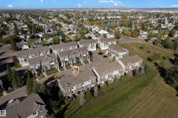 Aerial perspective showcasing a residential development with multiple townhome units, surrounded by landscaped green spaces and mature trees - 