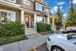 Siding exterior with multiple windows, concrete walkway, and landscaped shrubbery - 