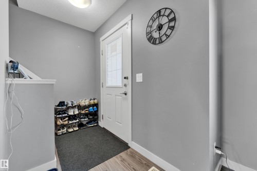 Entryway featuring a white door with frosted glass paneling, wood-finish flooring, and a flush-mount ceiling light - #22 4205 30 St Nw, Edmonton, AB 