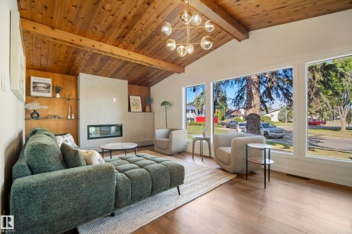 Vaulted wood-paneled ceiling with exposed beams, modern chandelier, integrated fireplace, built-in shelving, and wood-finish flooring - 10316 42 Street Nw, Edmonton, AB 