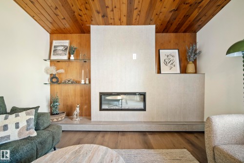 Wood-paneled ceiling, integrated linear fireplace, tiled fireplace surround, built-in shelving, and wood-finish flooring - 10316 42 Street Nw, Edmonton, AB 