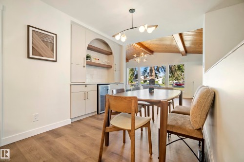 Wood-finish flooring throughout, built-in cabinetry with an arched display niche, recessed beverage refrigerator, contemporary lighting fixtures, and large picture windows - 10316 42 Street Nw, Edmonton, AB 