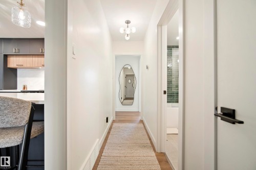 Hallway featuring wood-finish flooring, recessed lighting, and a modern light fixture - 10316 42 Street Nw, Edmonton, AB 