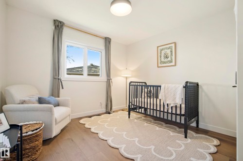Light wood-finish flooring, a double-pane window with neutral drapes, and a flush-mount ceiling light fixture - 10316 42 Street Nw, Edmonton, AB 