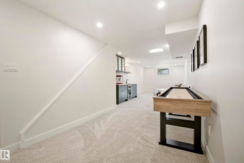 Spacious recreation room featuring recessed lighting, light-toned carpeting, and a built-in wet bar with dark cabinetry - 10316 42 Street Nw, Edmonton, AB 