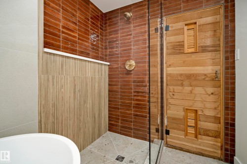 Walk-in shower with vertical wood-finish wall tile, brick-patterned tile, brass fixtures, and a wooden sauna door - 10316 42 Street Nw, Edmonton, AB 