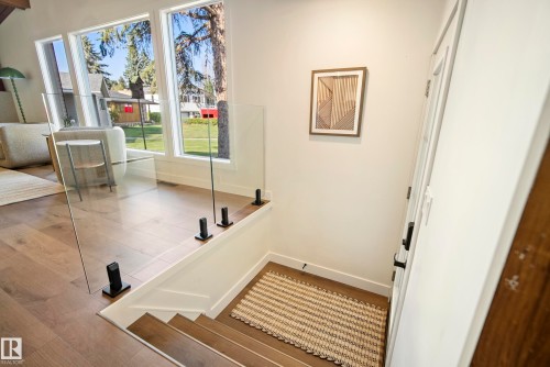 Hardwood flooring throughout, featuring a glass panel railing system with black hardware - 10316 42 Street Nw, Edmonton, AB 
