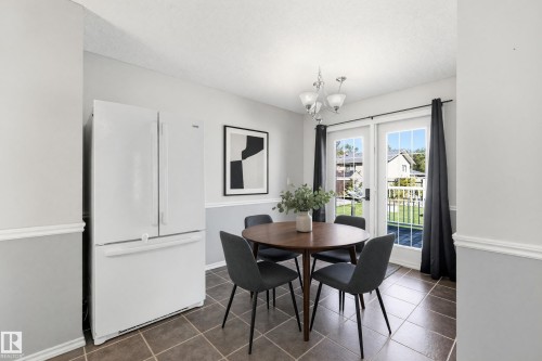 White French door refrigerator, two-tone wall treatment, tile flooring, white French doors, and a decorative ceiling light fixture - 74 Aspen Crescent, St. Albert, AB 