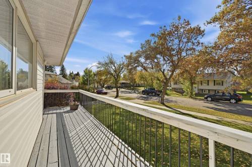 Balcony with a wood-finish deck, white siding, and black metal railings - 74 Aspen Crescent, St. Albert, AB 