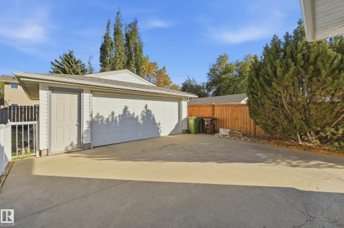 Detached two-car garage with a side entry door, concrete driveway, and wood privacy fencing - 74 Aspen Crescent, St. Albert, AB 
