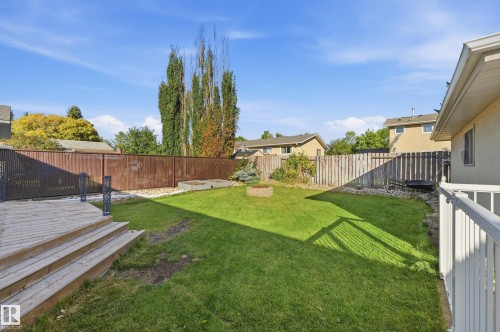 Expansive backyard featuring a wood deck, manicured lawn, and a built-in fire pit - 74 Aspen Crescent, St. Albert, AB 