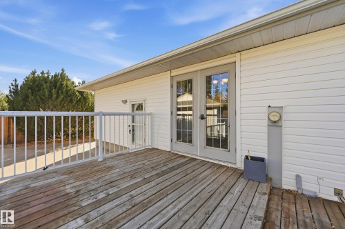 Wood deck with white railing, double glass-paneled doors, and white siding - 74 Aspen Crescent, St. Albert, AB 