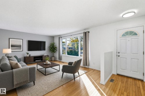 Hardwood flooring, large window, white trim, recessed lighting, and a front entry door with an arched transom window - 74 Aspen Crescent, St. Albert, AB 