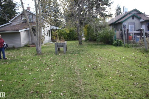 Expansive grassy yard area with mature trees and a raised garden bed - 5012 49 Ave, Radway, AB 
