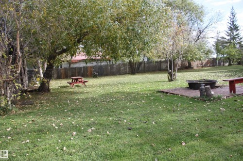 Expansive green lawn with mature trees and a privacy fence - 5012 49 Ave, Radway, AB 