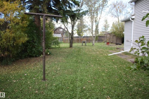 Expansive grassy yard with mature trees and a fenced perimeter - 5012 49 Ave, Radway, AB 