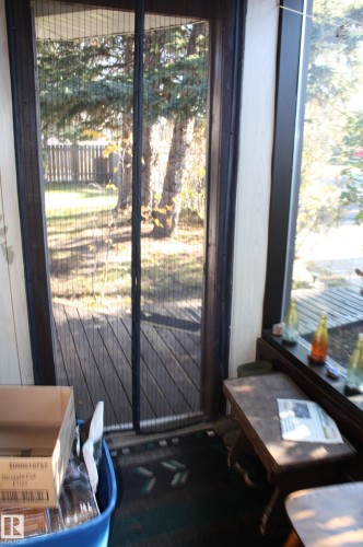 Screened door with full-height glazing, wood-plank decking, and expansive windows - 5012 49 Ave, Radway, AB 