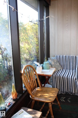 Floor-to-ceiling windows featuring dark-toned frames and vertical wood-paneled wall surfacing - 5012 49 Ave, Radway, AB 