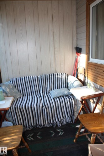 Enclosed porch featuring vertical paneling, horizontal wood-finish siding, and a white-frame window - 5012 49 Ave, Radway, AB 