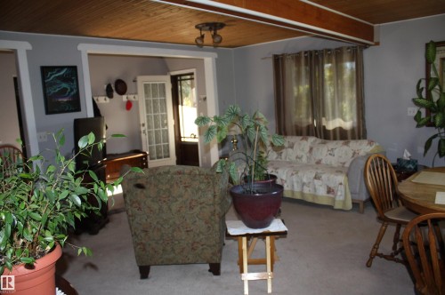 Wood-plank ceiling with exposed structural beam, white-trimmed door frames, and glass-paned exterior door - 5012 49 Ave, Radway, AB 