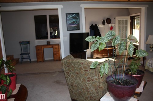 Interior space featuring wood-plank ceiling treatment, wall-to-wall carpeting, and a multi-pane glass-panel door - 5012 49 Ave, Radway, AB 