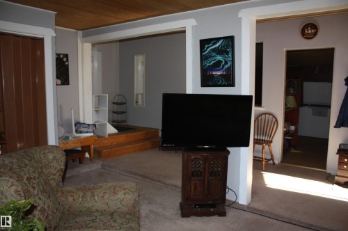 Interior space featuring white-trimmed doorways, wood-tone ceiling finishes, and a raised platform area with wood-finish step detailing - 5012 49 Ave, Radway, AB 