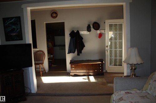 Entryway featuring a glass-panel door, wall-mounted coat hooks, and carpeted flooring - 5012 49 Ave, Radway, AB 